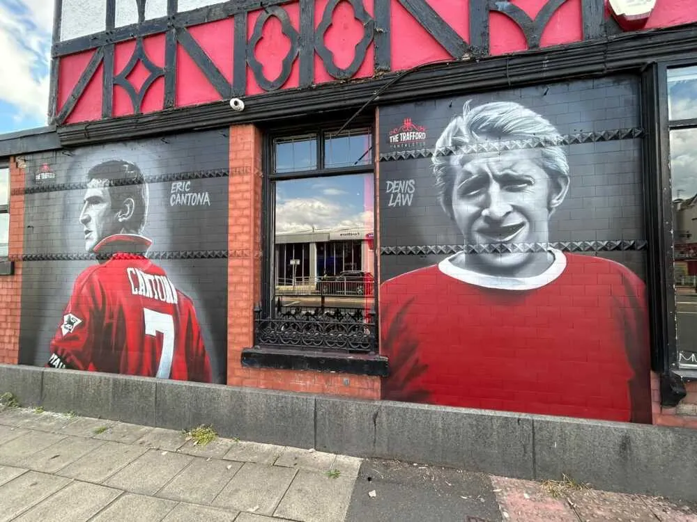 Paintings of Cantona and Law on the side of a pub in Manchester